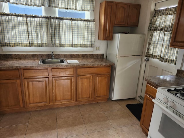 kitchen with white appliances, dark countertops, and brown cabinets