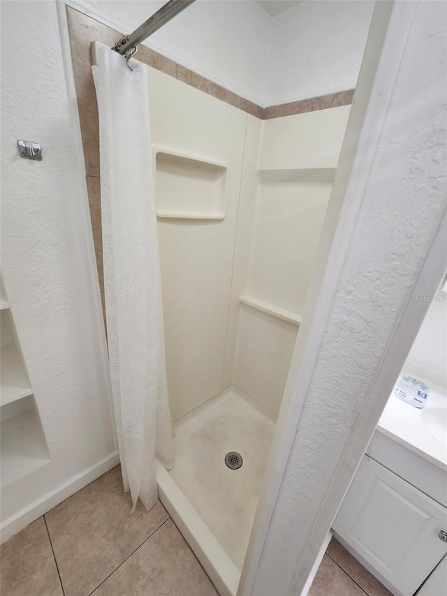 bathroom featuring tile patterned floors, a stall shower, and baseboards