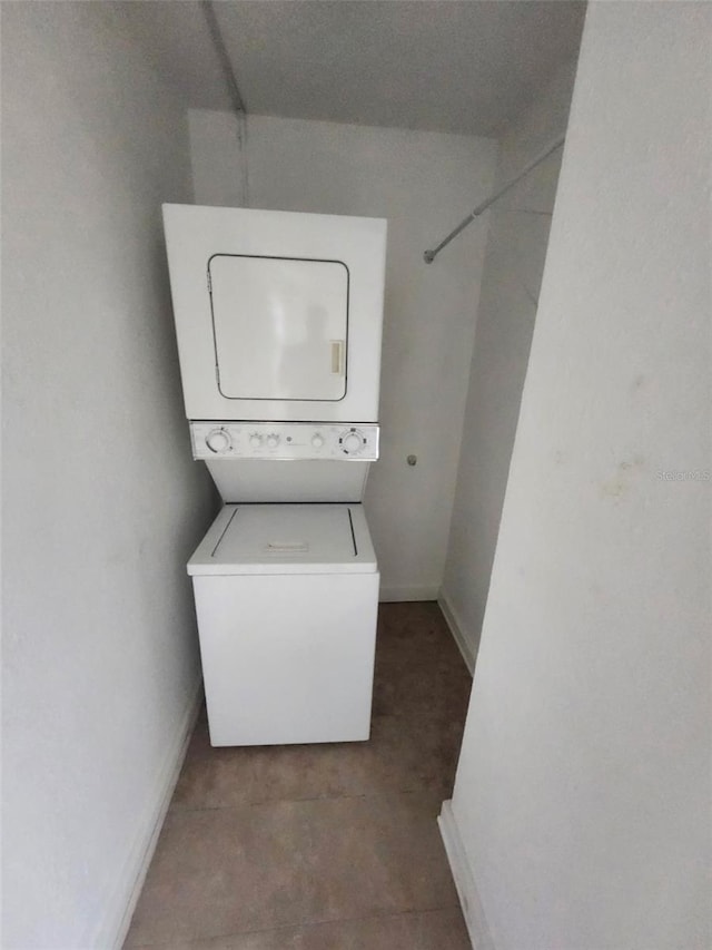 laundry area with laundry area, stacked washer / dryer, and baseboards