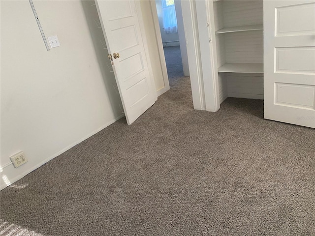 unfurnished bedroom with dark colored carpet and a closet