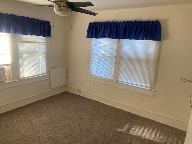 unfurnished room with dark colored carpet, baseboards, and a ceiling fan