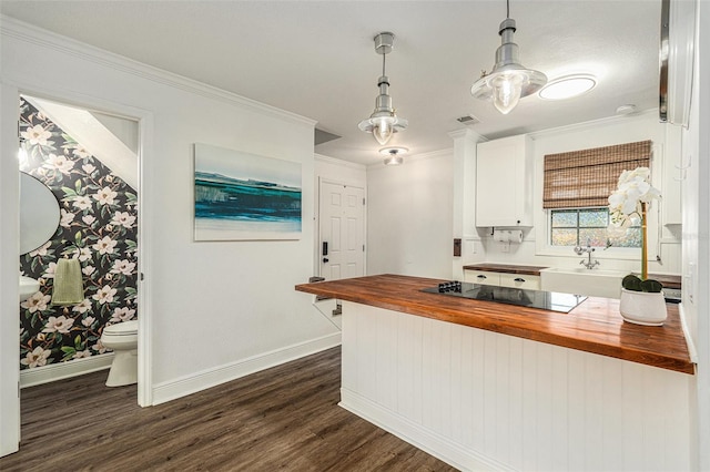 kitchen with butcher block countertops, crown molding, dark wood-type flooring, black electric stovetop, and white cabinets