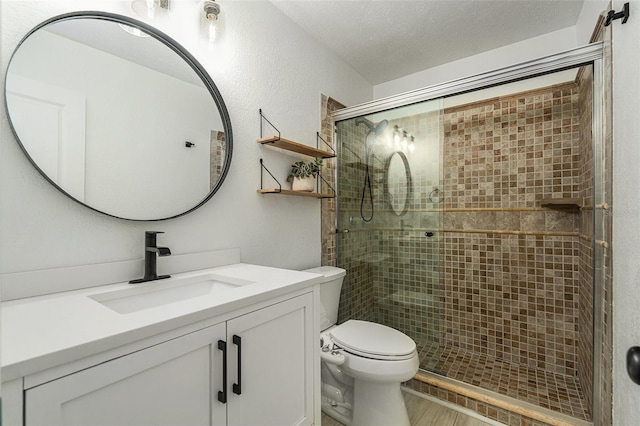 bathroom featuring vanity, toilet, a textured ceiling, and walk in shower