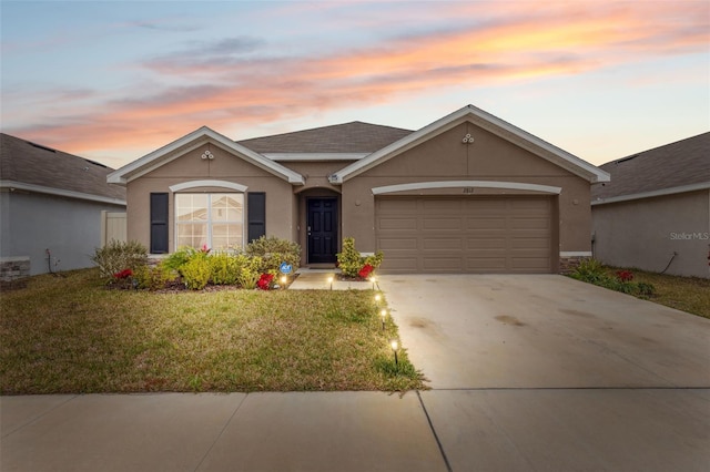 ranch-style home with a garage and a lawn