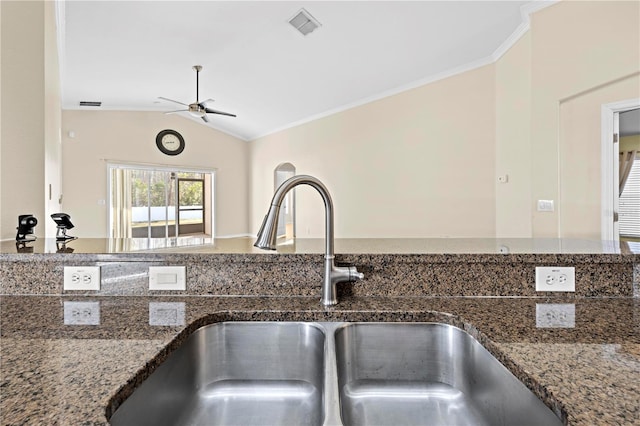 kitchen featuring ornamental molding, vaulted ceiling, sink, and dark stone countertops