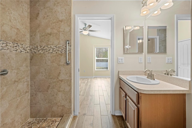 bathroom featuring ceiling fan, vanity, vaulted ceiling, and a tile shower