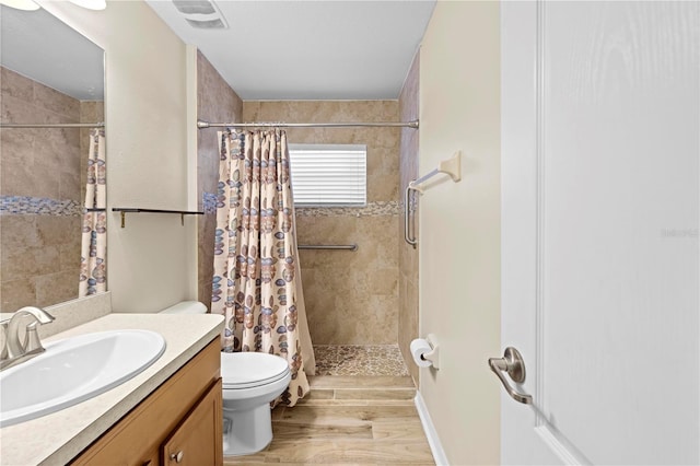 bathroom featuring vanity, wood-type flooring, toilet, and walk in shower