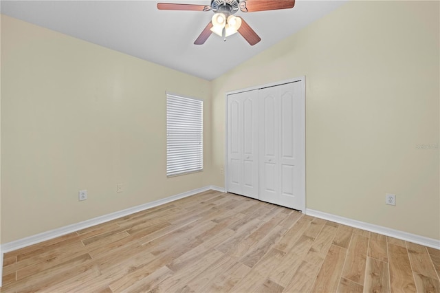 unfurnished bedroom featuring ceiling fan, vaulted ceiling, a closet, and light wood-type flooring