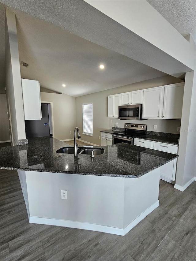 kitchen featuring sink, stainless steel appliances, kitchen peninsula, white cabinets, and dark stone counters