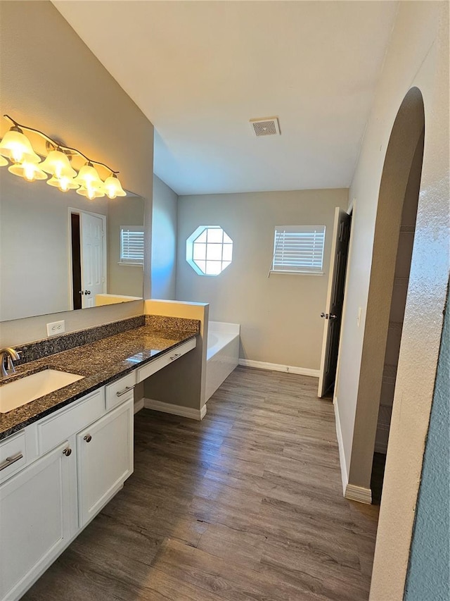 bathroom with vanity, a bath, and hardwood / wood-style flooring