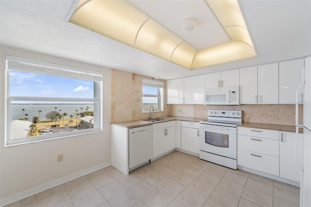 kitchen with white appliances, sink, decorative backsplash, and white cabinets