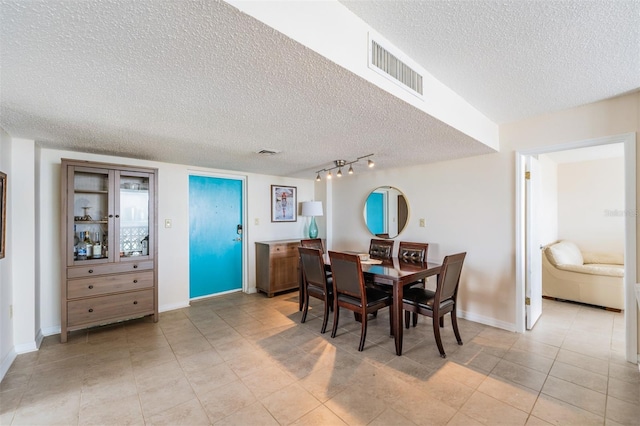 dining area featuring light tile patterned floors and a textured ceiling