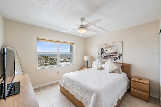 tiled bedroom with ceiling fan and a textured ceiling