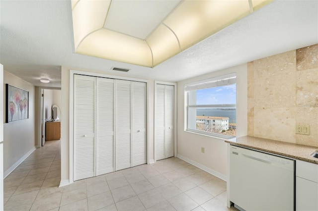 interior space with white dishwasher, light tile patterned floors, and a textured ceiling