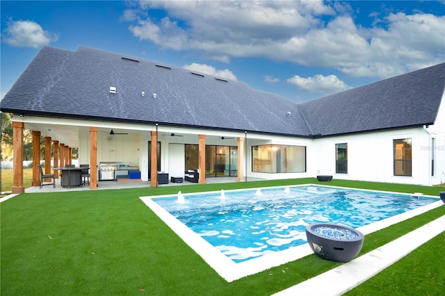 rear view of property with an outdoor living space with a fire pit, a patio area, ceiling fan, and a lawn