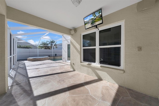 view of patio / terrace with an outdoor hot tub and a lanai