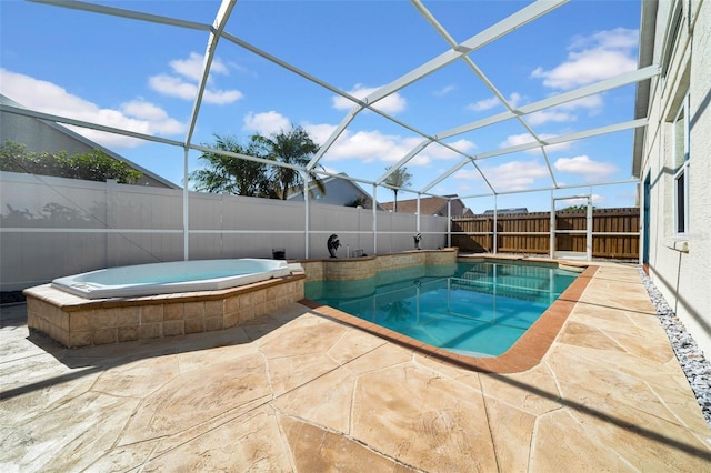 view of pool with an in ground hot tub, a patio area, and glass enclosure