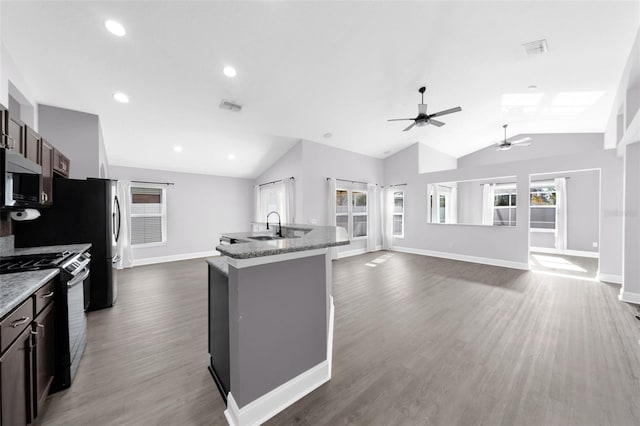 kitchen with dark brown cabinetry, black range with gas stovetop, vaulted ceiling, and an island with sink