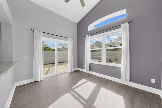 unfurnished dining area featuring high vaulted ceiling, dark hardwood / wood-style floors, and ceiling fan