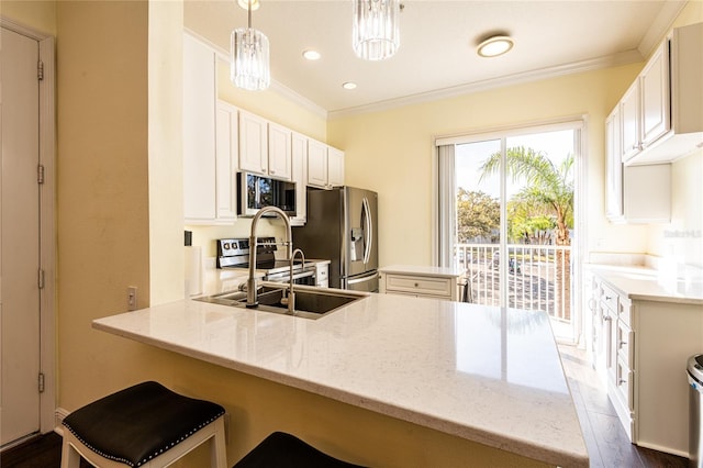 kitchen featuring sink, hanging light fixtures, stainless steel appliances, a kitchen bar, and kitchen peninsula