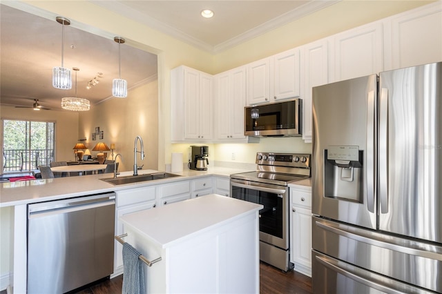 kitchen featuring sink, ornamental molding, appliances with stainless steel finishes, pendant lighting, and white cabinets