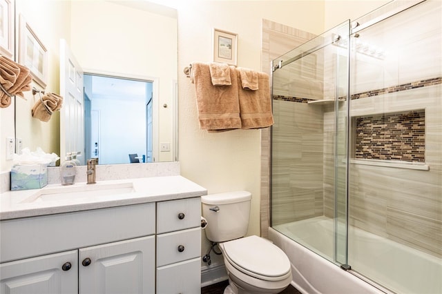 full bathroom with vanity, bath / shower combo with glass door, and toilet