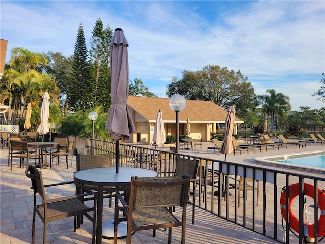 wooden deck with a community pool and a patio area