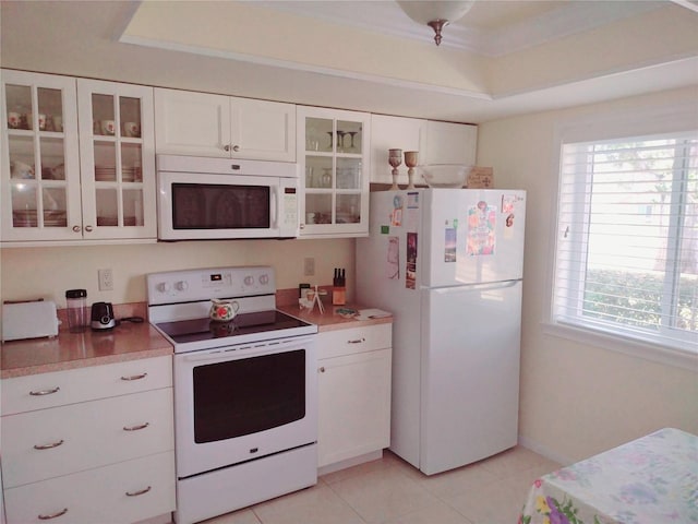 kitchen featuring white appliances, a raised ceiling, white cabinets, and light tile patterned flooring