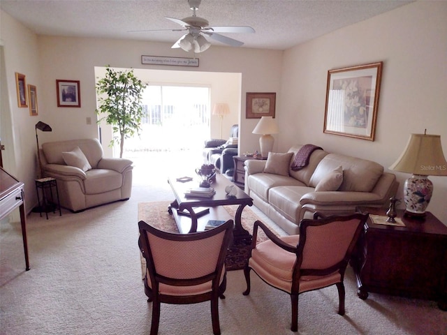 carpeted living room featuring ceiling fan and a textured ceiling