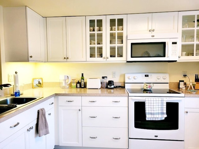 kitchen with sink, white cabinets, and white appliances