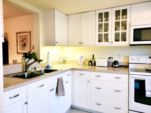 kitchen with white cabinetry, sink, white appliances, and light tile patterned floors