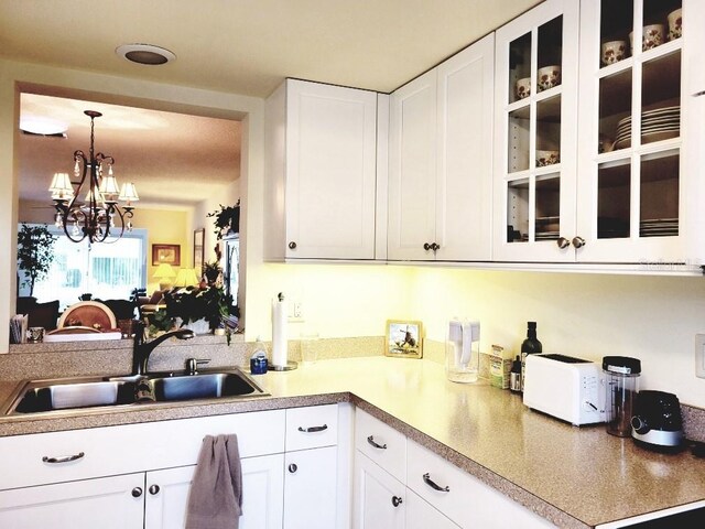 kitchen featuring hanging light fixtures, white cabinetry, sink, and a chandelier