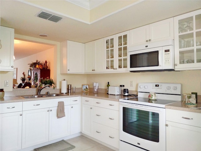 kitchen with sink, white appliances, light tile patterned floors, and white cabinets