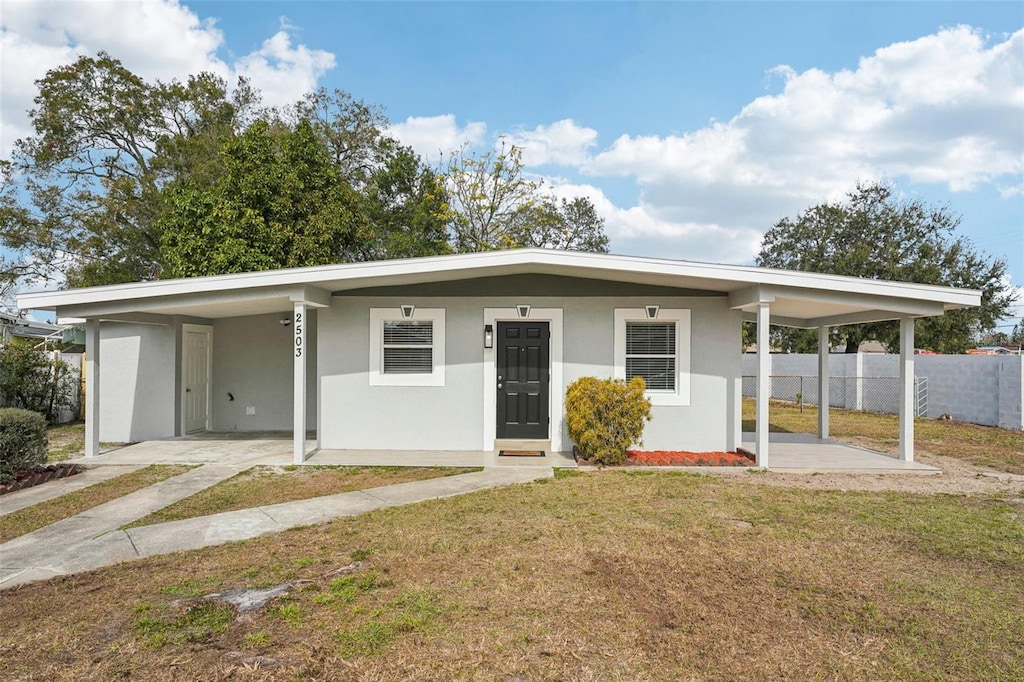 ranch-style home featuring a carport and a front lawn