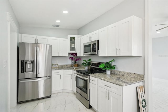 kitchen featuring stainless steel appliances, light stone countertops, and white cabinets