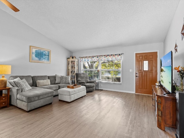 living room with vaulted ceiling, a textured ceiling, and light hardwood / wood-style flooring