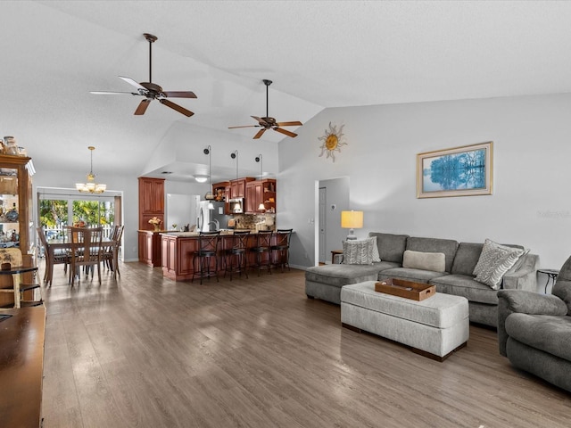 living room featuring high vaulted ceiling, ceiling fan with notable chandelier, and dark hardwood / wood-style flooring