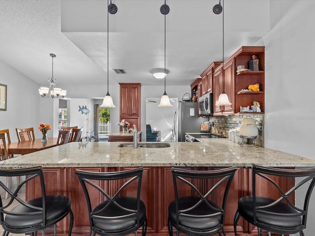 kitchen featuring sink, tasteful backsplash, decorative light fixtures, appliances with stainless steel finishes, and kitchen peninsula