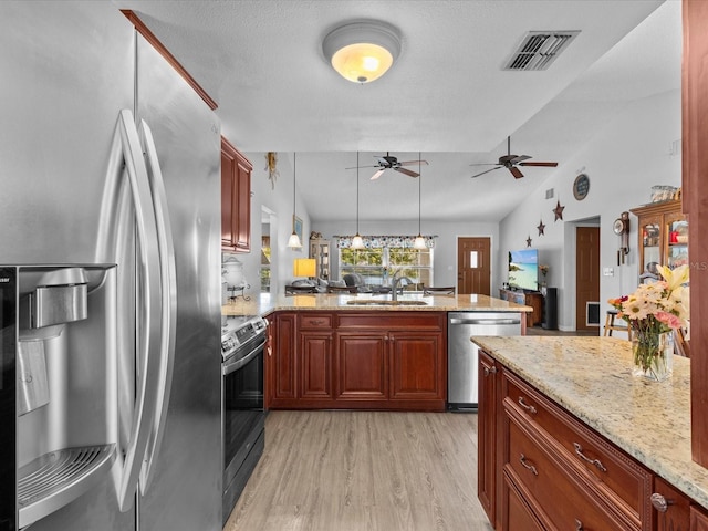 kitchen with appliances with stainless steel finishes, pendant lighting, sink, kitchen peninsula, and light wood-type flooring