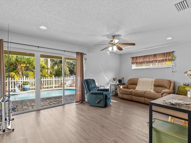 living room with ceiling fan, wood-type flooring, and a textured ceiling