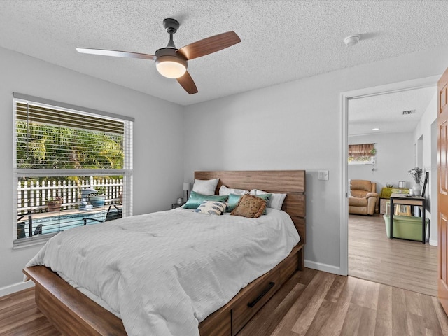 bedroom with ceiling fan, hardwood / wood-style floors, and a textured ceiling