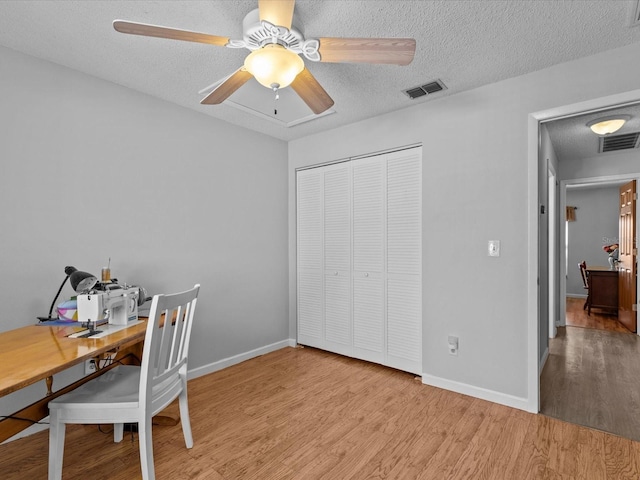 home office with ceiling fan, a textured ceiling, and light wood-type flooring