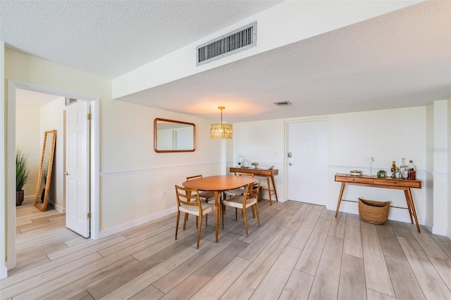 dining space with a textured ceiling and light hardwood / wood-style flooring