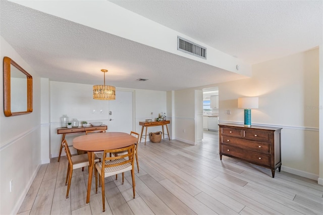 dining room with light hardwood / wood-style floors and a textured ceiling