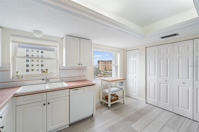 kitchen featuring sink, white cabinetry, tasteful backsplash, light hardwood / wood-style flooring, and dishwasher