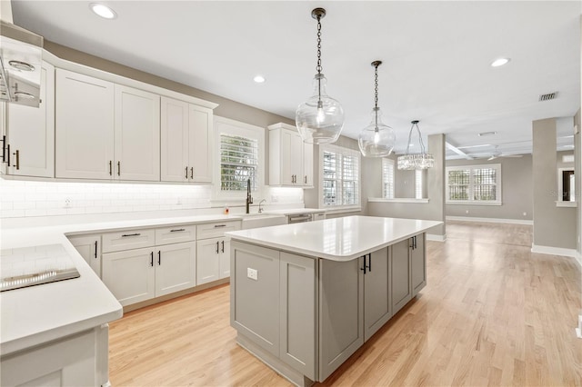 kitchen with hanging light fixtures, a center island, sink, and white cabinets