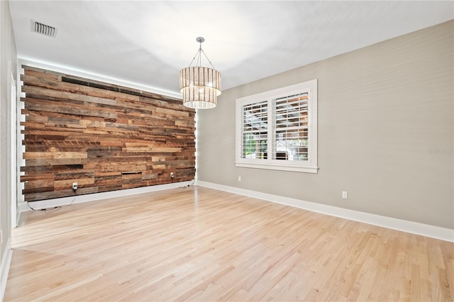 spare room with a chandelier and light wood-type flooring