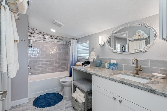 full bathroom featuring shower / tub combo with curtain, vanity, toilet, and a textured ceiling