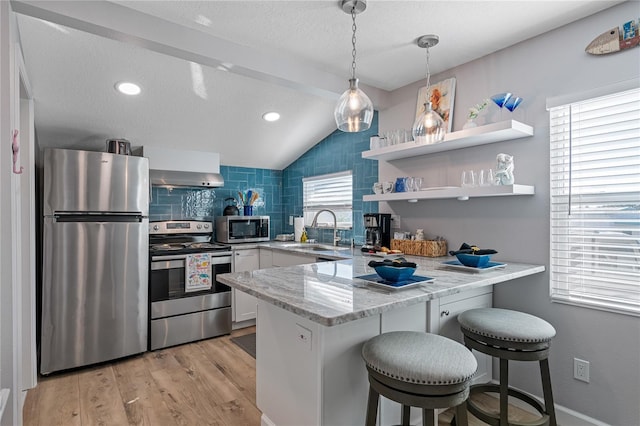 kitchen with sink, a breakfast bar area, white cabinetry, appliances with stainless steel finishes, and kitchen peninsula