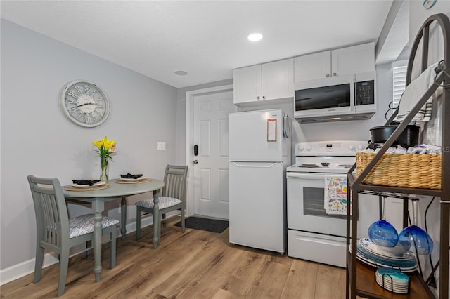 kitchen with white cabinets, white appliances, and light hardwood / wood-style flooring